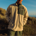 Guy weraing a sherpa jacket with a beach background